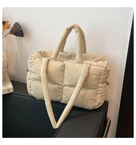 Detail of beige quilted tote bag showing padded stitching and adjustable drawstring side