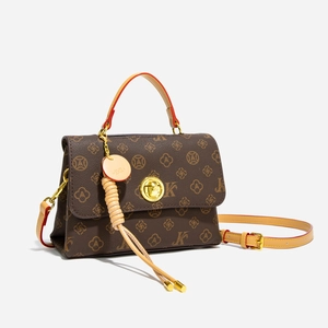 Detail of vintage patterned crossbody bag with golden metal twist lock and leather strap