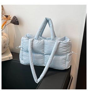 Detail of light blue quilted puffer tote bag with adjustable drawstring on side