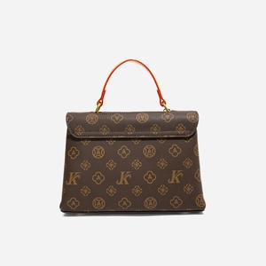 Detail of vintage patterned crossbody bag with a red handle and brown leather finish