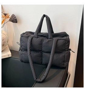 Close-up of black quilted tote bag featuring dual handles and side drawstring details