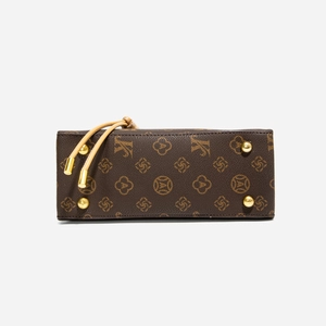 Close-up of vintage printed handbag base with gold metal feet and monogram texture