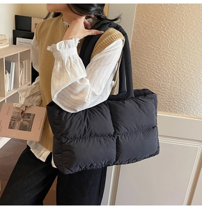 Close-up of a black quilted puffer tote bag with soft padded handles and large capacity