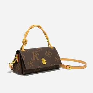 Detailansicht der braunen Monogramm-Tasche mit gelbem Seilgriff und goldener Schließe