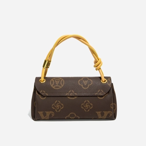 Detail der dunkelbraunen Handtasche mit Monogramm-Muster und gelbem Flechtgriff