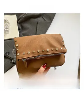 Detailed macro view of the brown suede texture and silver metal studs on the chain bag