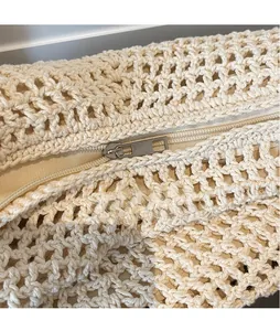 Close-up of crochet hollow weave texture with silver metal zipper and light brown lining