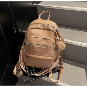 Macro detail of camel faux leather backpack with silver zippers and plush ball charm