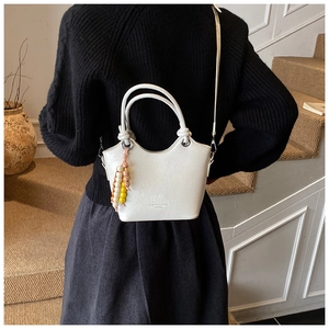 Detailed shot of white litchi pattern bucket bag with colorful beaded charm and long strap