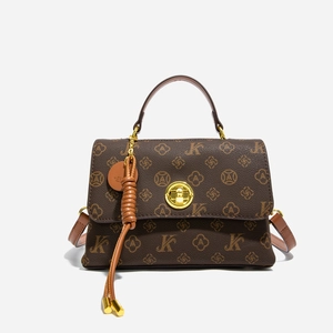 Detail of vintage brown monogram handbag featuring gold circular twist lock and leather tassel