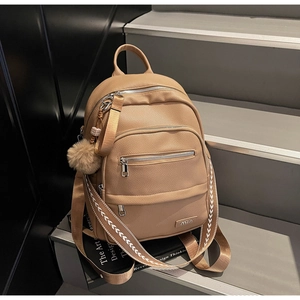 Detail of khaki pebbled leather backpack with silver zippers and plush ball charm