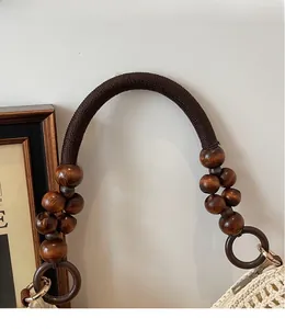 Detail of woven tote shoulder strap with dark brown wooden beads and a secure metal zipper