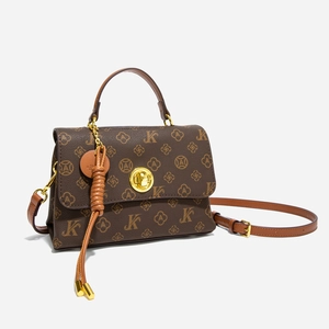 Detail view of vintage patterned crossbody bag with gold clasp and tassel charm