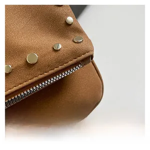 Close-up of brown litchi texture leather shoulder bag with silver studs and zipper details