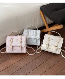 Detailed view of three cute cartoon backpacks in pink, blue, and white with buckle straps