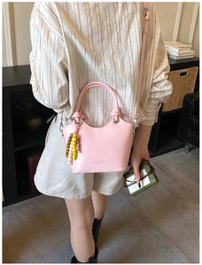 Pink PU leather bucket bag detail showing fashion lettering and beaded charm handle