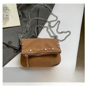 Detailed macro view of the brown suede crossbody bag with silver studs and chain strap