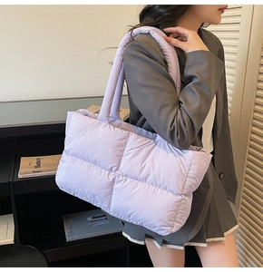Detail of light purple quilted puffer tote bag on shoulder with plush puffy texture