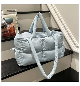 Detail of light blue quilted tote bag with soft texture and adjustable drawstring on side