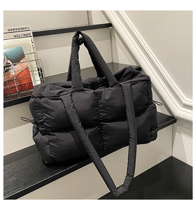 Close-up of black quilted puffer tote bag with dual handles and padded texture