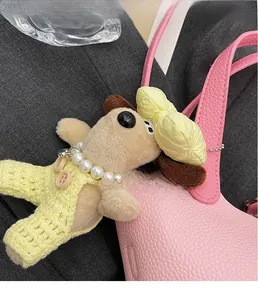 Plush puppy charm with knitted overalls and pearl necklace on pink textured bag