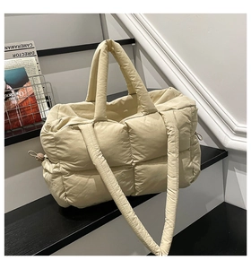 Close-up of beige quilted tote bag with side drawstrings and soft texture detail