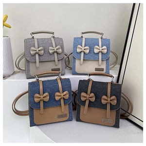 Collection of preppy bow backpacks in grey, blue and navy displayed with tulips