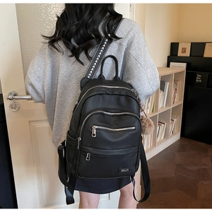 Detail of black pebbled leather backpack with multi-zipper pockets and geometric strap