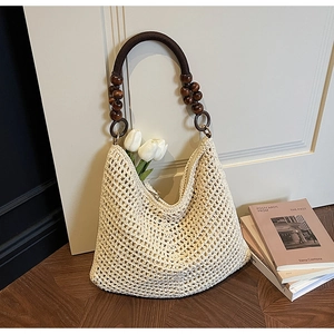 Detail of hollow knit tote bag featuring dark brown wooden bead handle and zipper closure