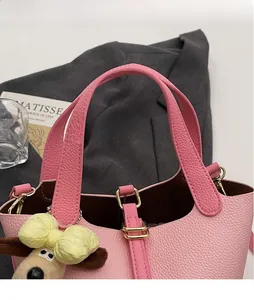 Close-up of pink lychee leather bucket bag with gold buckle and plush lamb charm