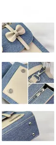 Detail of denim and beige leather tote with bow clasp, metal studs, and smooth zipper