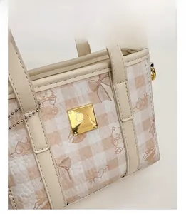 Close-up of beige checkered bucket bag featuring gold cat logo and premium faux leather