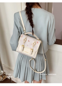 Detail of cream crossbody bag featuring pink cartoon bear prints and golden logo lettering