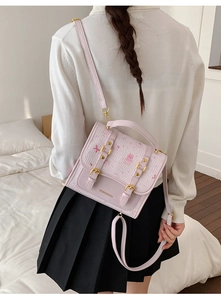Detail of pink crossbody bag with cartoon embossing and golden metallic buckles