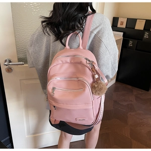 Detail of pink faux leather backpack with multiple zippers and white patterned strap decor