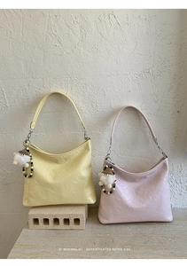 Detailed view of retro hobo bags in yellow and pink leather with plush doll charms
