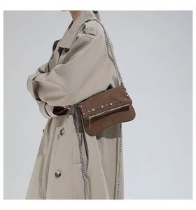 Close-up of a dark brown studded leather shoulder bag with silver chain and metal zipper