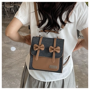 Detail of vintage denim and brown leather patchwork backpack with bow accents