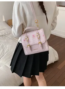 Detail of light purple cartoon crossbody bag with gold hardware worn by a model