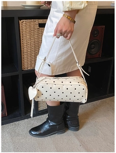 Polka dot cylindrical handbag featuring heart leather pendant and adjustable shoulder strap