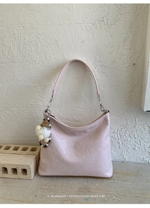 Detail of light pink wrinkled leather hobo bag featuring a cute plush dwarf pendant