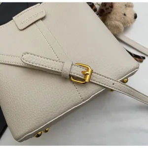 Dettaglio borsa beige in pelle martellata con fibbia dorata e cuciture a V
