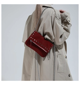 Detail view of burgundy suede shoulder bag with silver stud rivets and chain strap