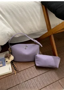 Dettaglio della borsa in pelle viola con chiusura in metallo e ciondolo a orsetto su legno