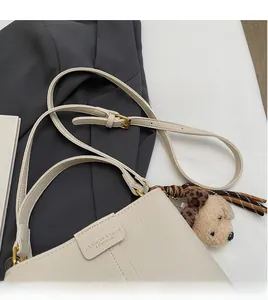 Dettaglio borsa a tracolla in pelle martellata bianco sporco con fibbie dorate e teddy