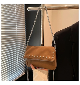 Detail view of the brown suede crossbody bag featuring silver studs and metal chain strap