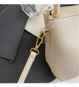 Dettaglio della pelle martellata bianca e fibbie in metallo dorato della borsa