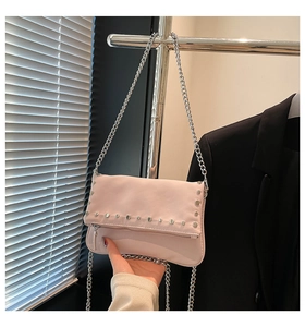 Detailed shot of pink studded shoulder bag with silver chain and matte leather texture