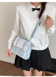Detail of light blue crossbody bag with bear print and adjustable gold buckle strap