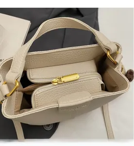 Dettaglio interno della borsa a secchiello beige con tasca e cerniera in metallo dorato
